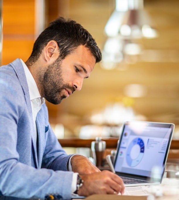 Empresario escribiendo en un documento sentado en una oficina moderna, destacando las soluciones de contratación estratégica de Avendra International para el crecimiento y la eficiencia de las empresas.