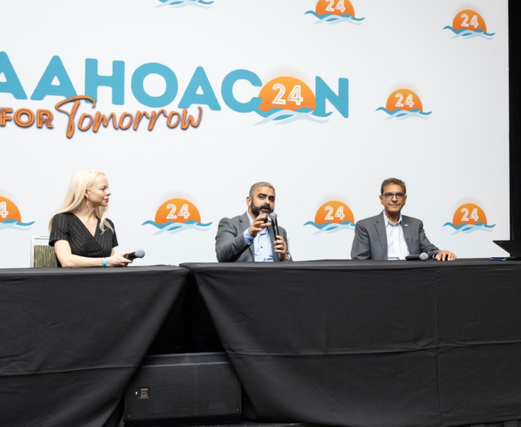Trois panélistes assis à une table avec des microphones, engagés dans une discussion à l'Asian American Hotel Owners Association.