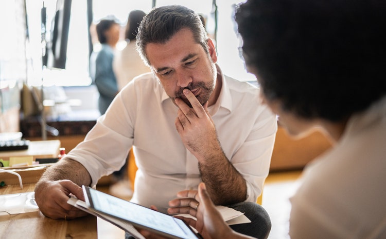 Homme mûr examinant des données d'assurance qualité sur une tablette numérique pour Avendra International, solutions d'approvisionnement.