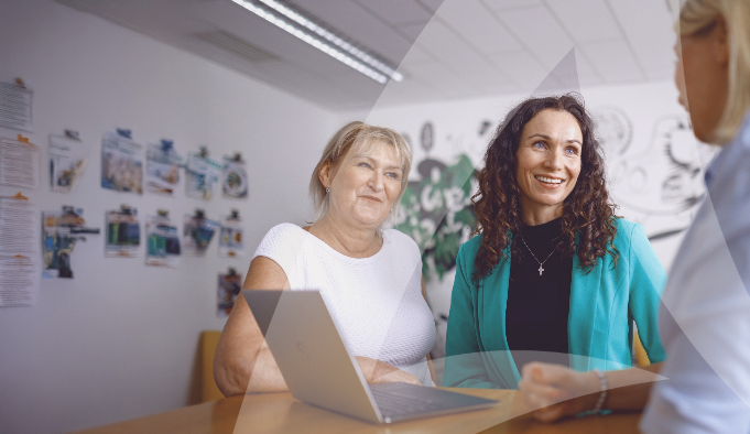 Trois femmes réunies autour d'une table, engagées dans une conversation.