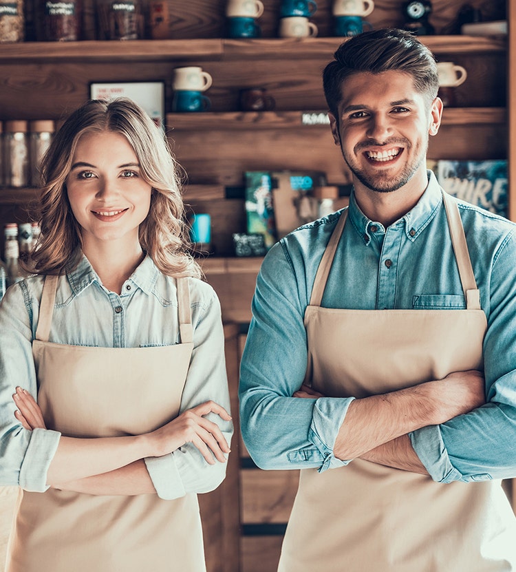 Un homme et une femme portant des tabliers, les bras croisés, souriant.
