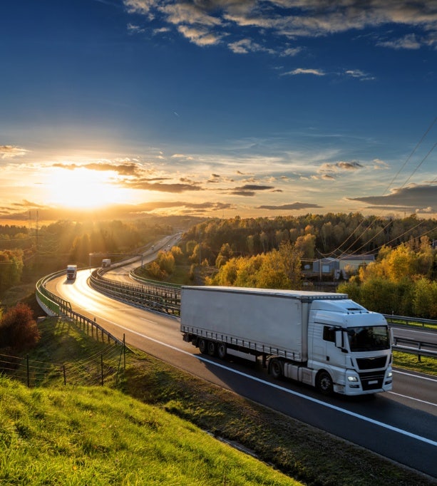 Grote vrachtwagen rijdt langs een snelweg bij zonsondergang