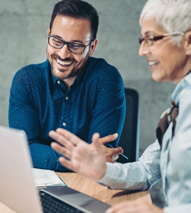 Man en vrouw glimlachen terwijl ze naar een laptopscherm kijken.