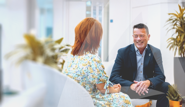 Man and a woman seated and chatting in a brightly lit office environment