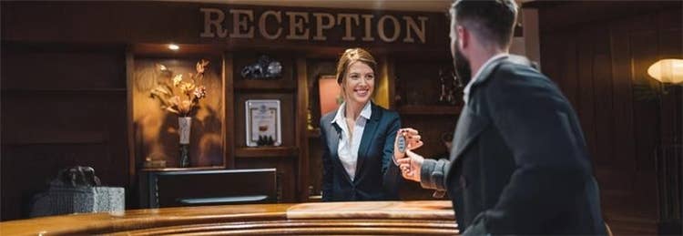 Hotel receptionist handing over the key card to the guest.
