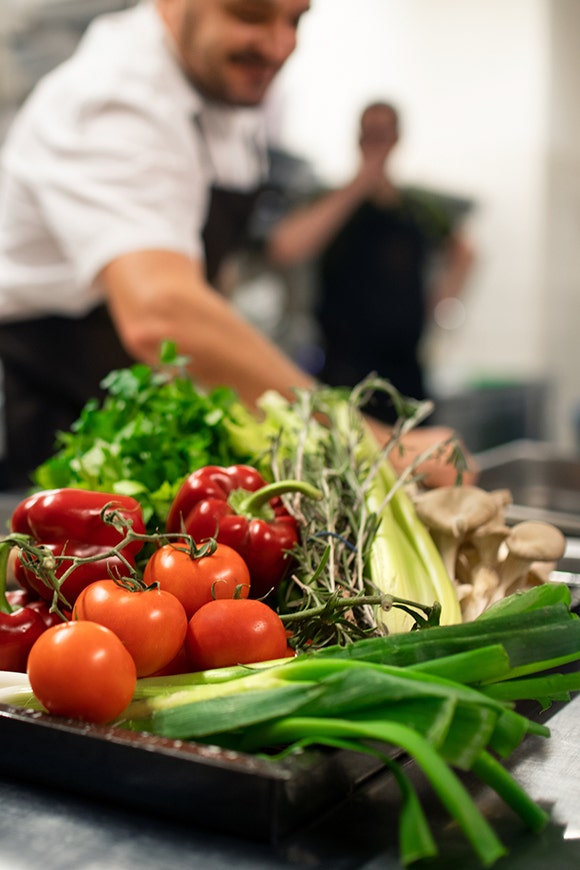 Assortment of fresh vegetables with chefs in the background
