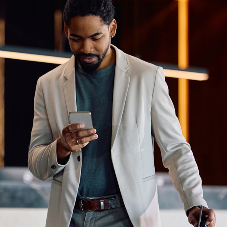 Man holding a suitcase checking his phone.