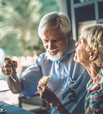 Oudere man en vrouw genieten samen van een maaltijd