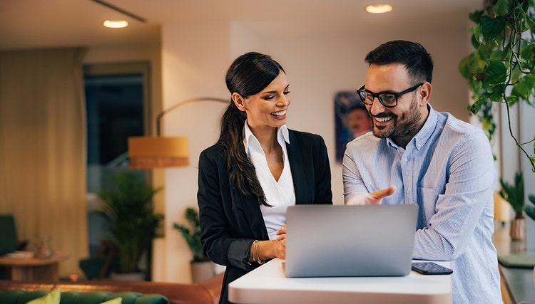 Man en vrouw glimlachen terwijl ze naar een laptopscherm kijken.