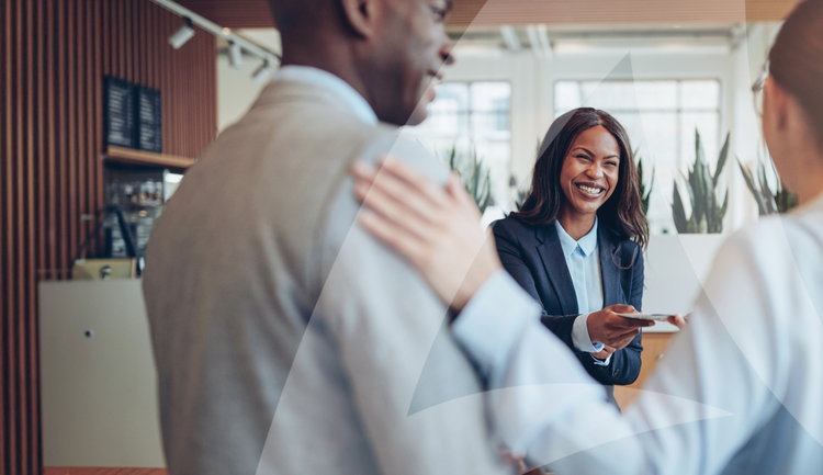 Vrouw die glimlacht terwijl ze een stuk papier aan een collega overhandigt